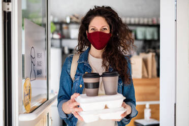 A woman with packed take away food and coffee, looking at camera. Coronavirus concept. - HPIF05572