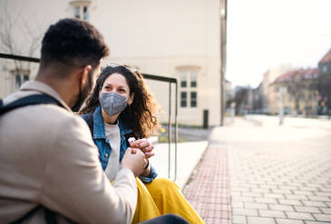 Young man giving flower to woman outdoors in city, coronavirus, love and back to normal concept. - HPIF05583