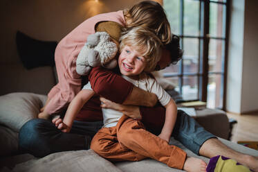 Ein erwachsener Vater mit zwei kleinen Kindern, die sich zu Hause ausruhen und spielen. - HPIF05592