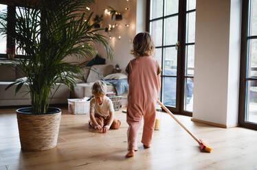 Zwei kleine Kinder fegen zu Hause, ein Konzept für die tägliche Hausarbeit. - HPIF05611