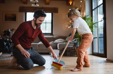 Vater mit kleinem Sohn, der zu Hause fegt, Konzept der täglichen Hausarbeit. - HPIF05613