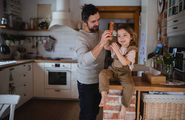 Ein reifer Vater mit einer kleinen Tochter, die sich zu Hause ausruht und die Haare kämmt. - HPIF05616