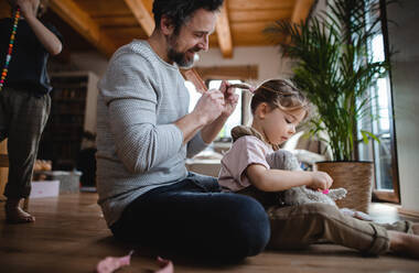 Ein reifer Vater mit seinem kleinen Sohn und seiner Tochter, die sich zu Hause ausruhen, spielen und die Haare kämmen. - HPIF05617