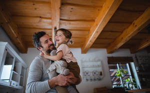 Niedriger Blickwinkel auf einen reifen Vater mit einer kleinen Tochter, die sich zu Hause amüsieren, sich umarmen und halten. - HPIF05620