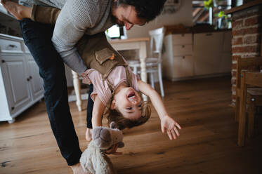 Ein reifer Vater mit einer kleinen Tochter, die zu Hause spielt und sie auf dem Kopf hält. - HPIF05621