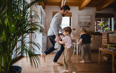 Ein erwachsener Vater mit zwei kleinen Kindern tanzt zu Hause im Haus. - HPIF05623