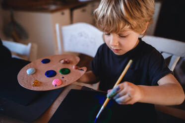 Ein konzentrierter kleiner Junge malt Bilder zu Hause in der Freizeit - HPIF05630