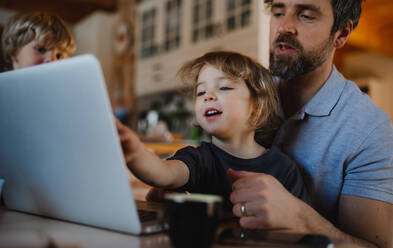 Ein halbwüchsiger Vater mit kleinen Kindern, der zu Hause arbeitet, Konzept des Home Office. - HPIF05644