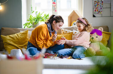 Happy sisters indoors at home, painting fingernails. Lockdown concept. - HPIF05689