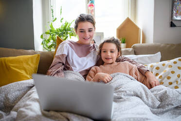 Porträt von Schwestern zu Hause, die einen Laptop benutzen, Konzept der Abriegelung. - HPIF05707