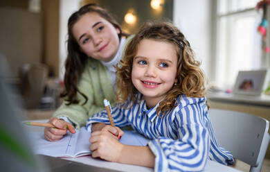 Portrait of sisters schoolgirls learning online indoors at home, coronavirus concept. - HPIF05727