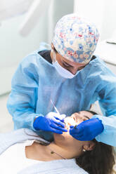 Junge Zahnärztin untersucht die Zähne eines Patienten mit Werkzeugen in der Klinik - JAQF01168