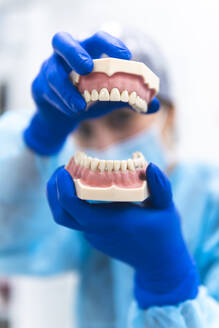 Hände eines Zahnarztes mit prothetischen Zähnen in einer Klinik - JAQF01172