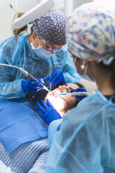 Zahnarzt mit Assistentin bei der Untersuchung eines Patienten mit Werkzeugen und Geräten in der Klinik - JAQF01176