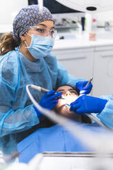 Zahnärztin mit Schutzbrille bei der Untersuchung eines Patienten in der Klinik - JAQF01177