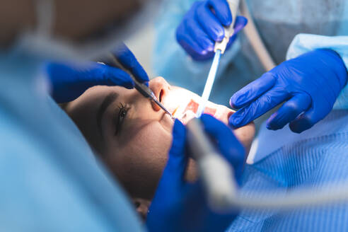 Young dentist with assistant examining patient in clinic - JAQF01178