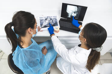 Junge Zahnärzte diskutieren über Röntgenbilder und benutzen Laptops in der Klinik - JAQF01189