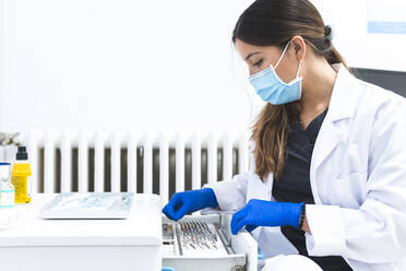 Dentist examining dental tools in drawer at clinic - JAQF01191