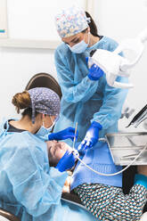 Dentist and assistant with equipment examining patient at clinic - JAQF01199