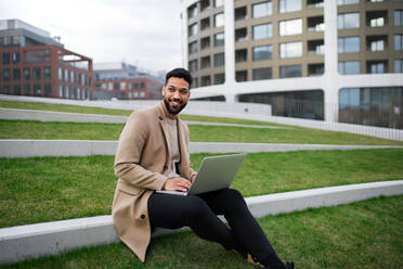 Junger Mann mit Laptop arbeitet im Freien im Park in der Stadt, Remote-Office-Konzept. - HPIF05759