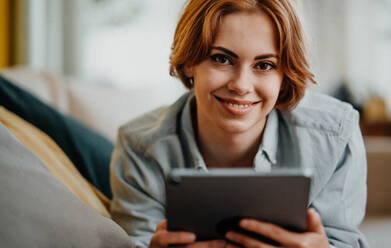 Portrait of a young woman using tablet, lying on sofa at home, social networks concept. - HPIF05774