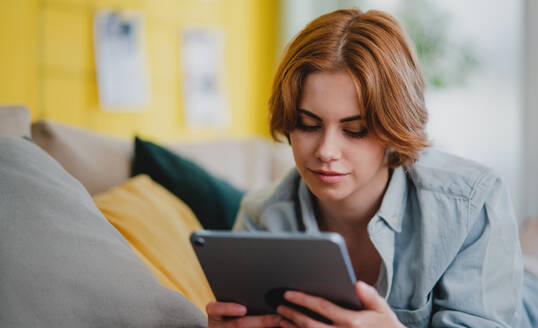 Porträt einer jungen Frau, die ein Smartphone benutzt, zu Hause auf dem Sofa liegend, Konzept für soziale Netzwerke. - HPIF05775