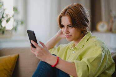 Ein Porträt der jungen Frau mit Smartphone nehmen selfie, drinnen zu Hause, soziale Netzwerke Konzept. - HPIF05780