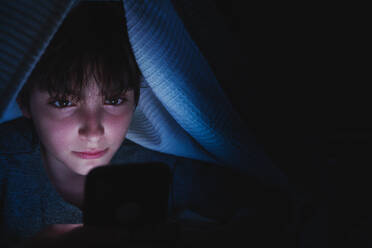 Teen girl using a smartphone, hiding under blanket at nigh, social networks cocnept. - HPIF05790