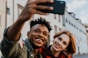 Junges gemischtrassiges Paar macht Selfie für soziale Netzwerke im Freien in einer Stadt. - HPIF05792