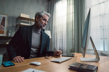 Ein reifer Geschäftsmann, der in einem Büro am Computer arbeitet. - HPIF05848