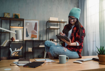 A happy female video editor works indoors in creative office studio. - HPIF05857