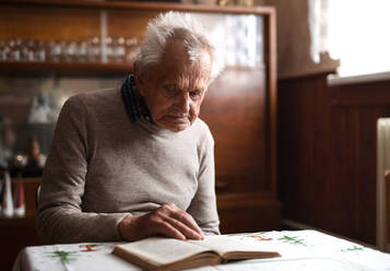 Ein Porträt eines älteren Mannes, der zu Hause am Tisch sitzt und sich ausruht. - HPIF05871