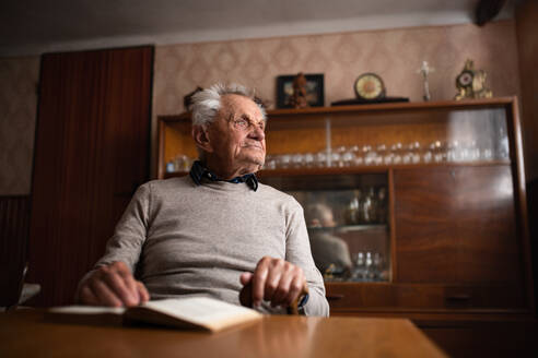 Ein Porträt eines älteren Mannes, der zu Hause am Tisch sitzt und sich ausruht. - HPIF05875