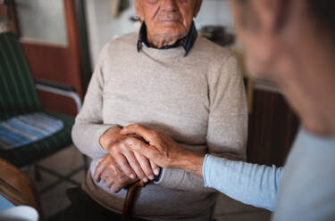 Midsection of unrecognizable man with elderly father sitting at the table indoors at home, talking. - HPIF05877