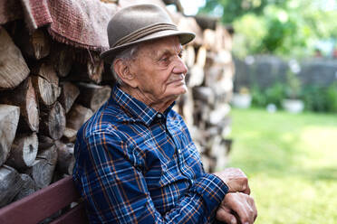 Ein Porträt eines älteren Mannes, der auf einer Bank im Garten sitzt und sich ausruht. - HPIF05881