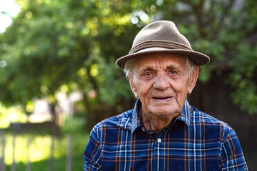 A portrait of elderly man standing outdoors in garden, looking at camera. - HPIF05886