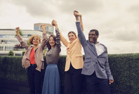 Cheerful businessman with colleagues celebrating on rooftop - PWF00611