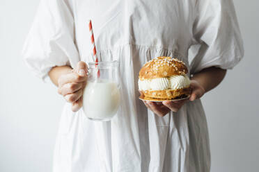 Frau mit Milchkanne und kleinem Kuchen vor weißer Wand - EGHF00700