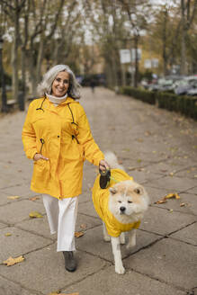 Glückliche ältere Frau mit Hund auf dem Fußweg - JCCMF08867