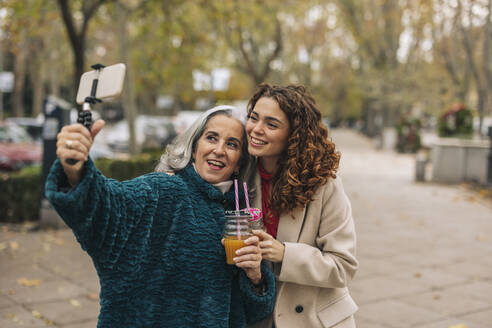 Glückliche Großmutter und Enkelin nehmen Selfie mit Glas Saft - JCCMF08871