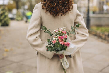 Young woman holding bouquet of flowers at footpath - JCCMF08872