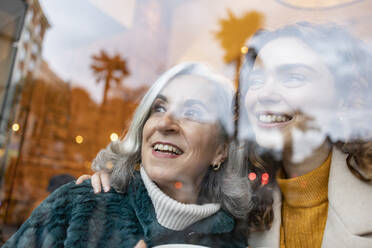 Happy young woman with grandmother seen through glass at cafe - JCCMF08930