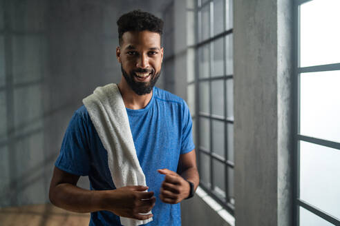 Porträt eines glücklichen jungen afroamerikanischen Sportlers, der im Fitnessstudio steht und in die Kamera schaut, Trainingskonzept. - HPIF05929