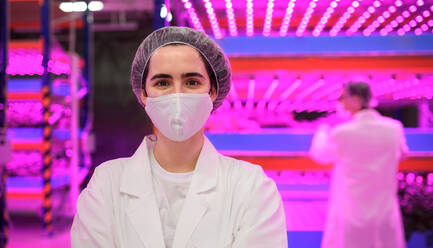 Front view of worker with face mask on aquaponic farm, sustainable business and coronavirus. - HPIF05977