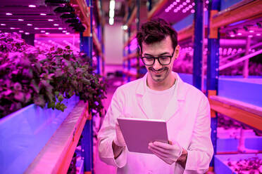 Portrait of worker with tablet on aquaponic farm, sustainable business and artificial lighting. - HPIF05980