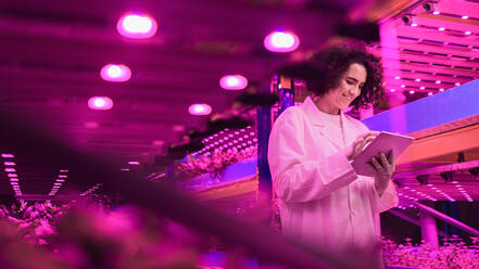 Portrait of worker with tablet on aquaponic farm, sustainable business and artificial lighting. - HPIF05987