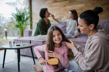 Two happy sisters with a mother and grandmother combing hair and doing make up together at home - HPIF06004