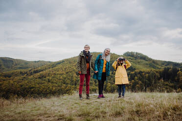A small girl with mother and grandmother hiking outoors in autumn nature. - HPIF06062