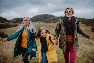 A small girl with mother and grandmother hiking outoors in autumn nature. - HPIF06064