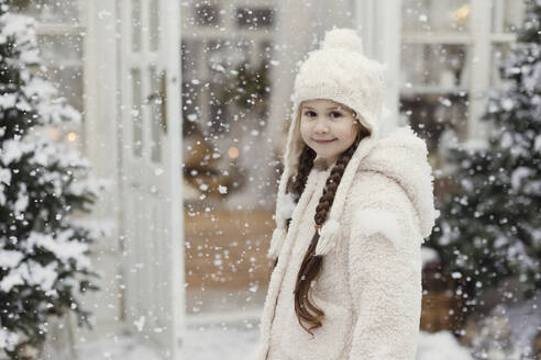 Lächelndes Mädchen mit geflochtenem Haar im Schnee stehend - ONAF00371